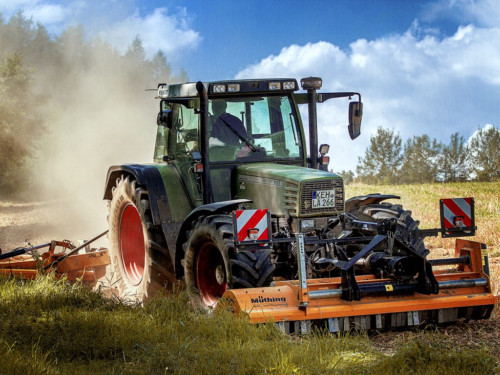Traktor bei der Grünlandarbeit im Staub