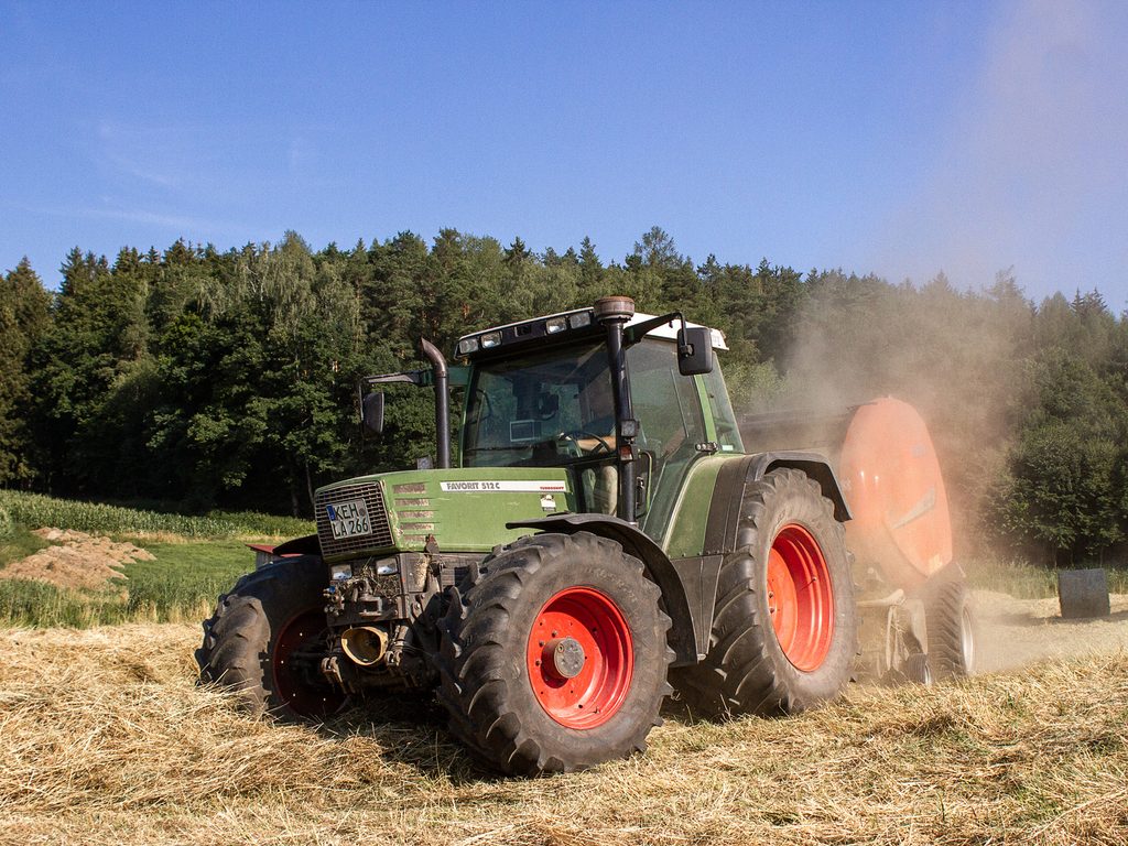 Traktor bei der Heuernte in einer Staubwolke