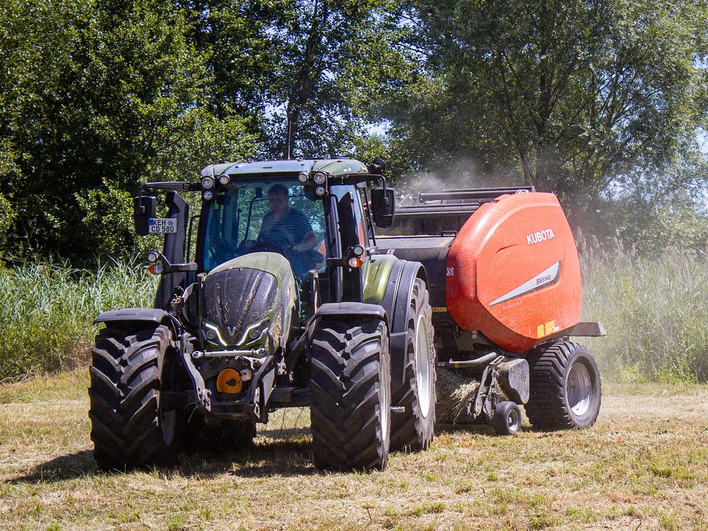 Traktor bei der Arbeit mit Rundballen